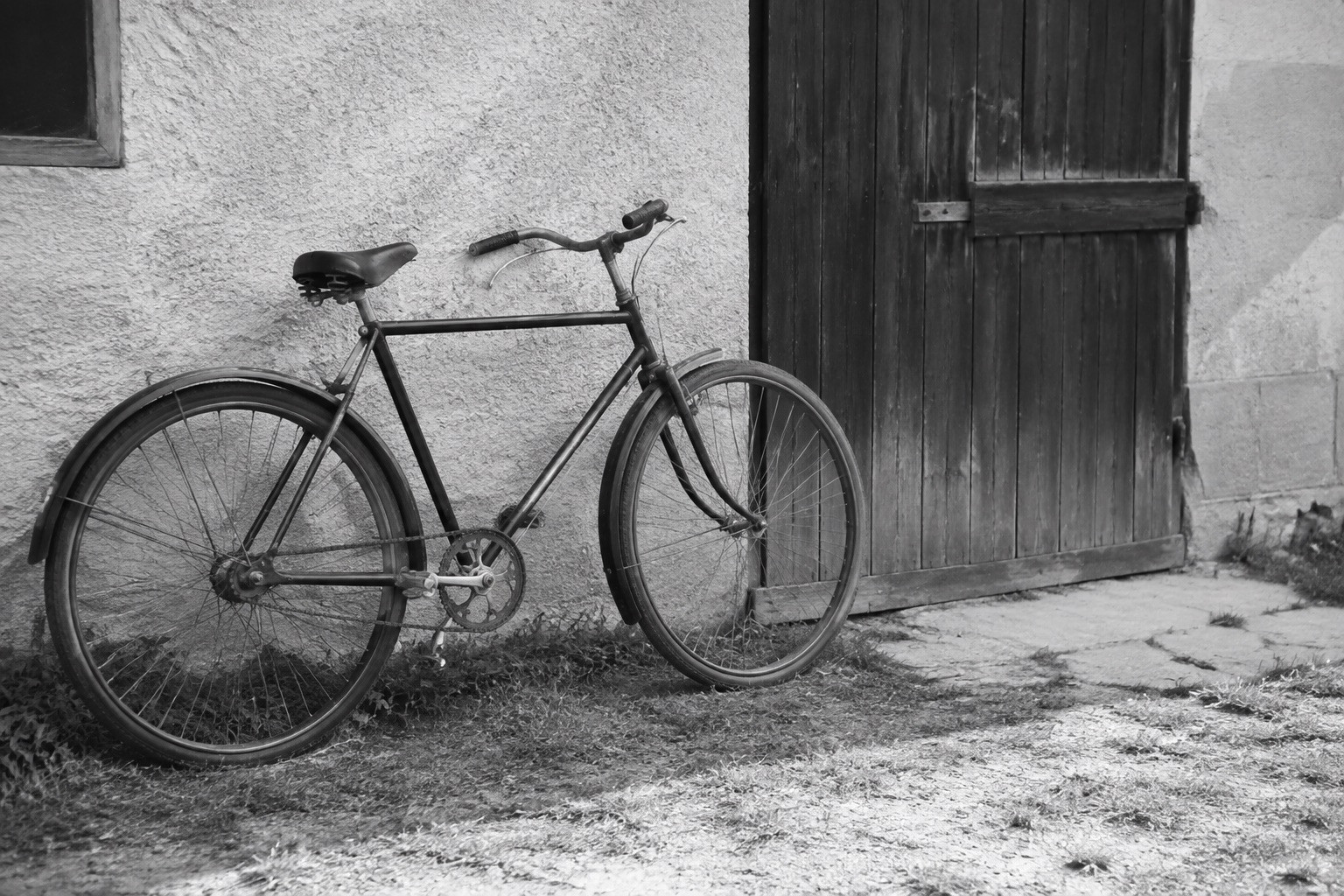 Ilustračná čiernobiela fotografia bicykla pri stodole